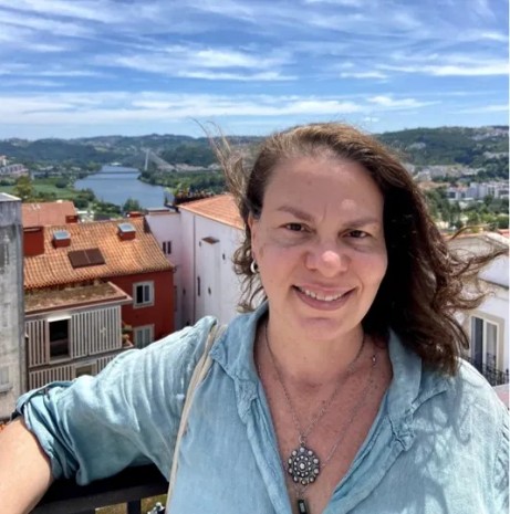 Fabiola Amorim smiling in front of a coastal town view